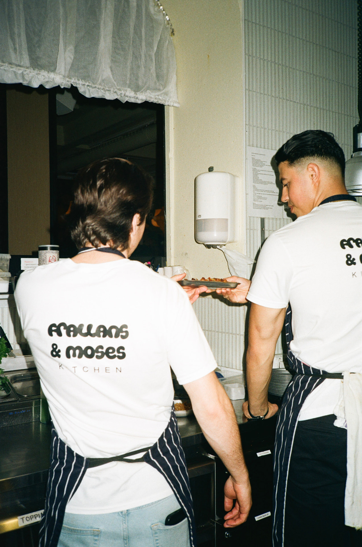 Två kockar i köket med Frallans & Moses Kitchen-tröjor